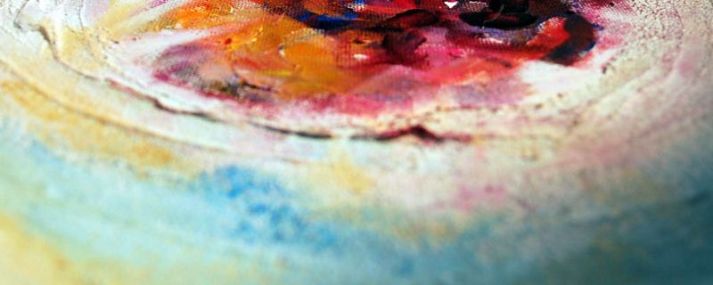A detail shot across the surface of a painted canvas, showing circular marks in warm colours against a ground of blue and green.