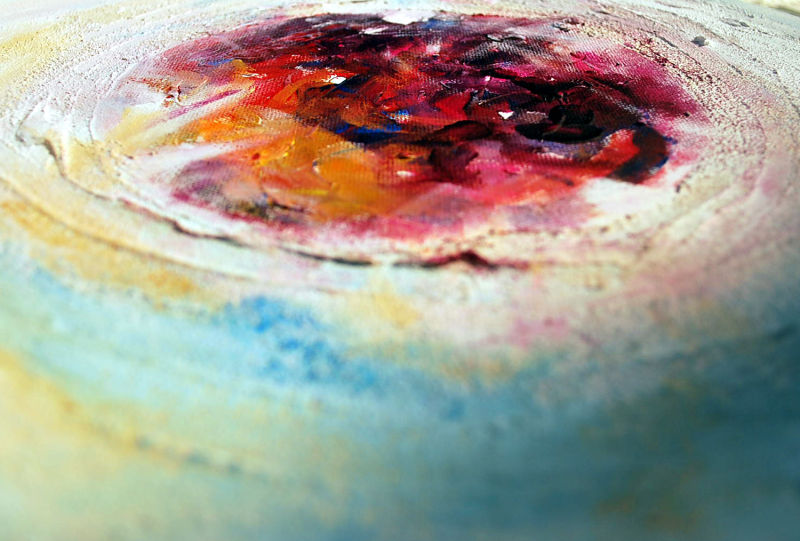 A detail shot across the surface of a painted canvas, showing circular marks in warm colours against a ground of blue and green.