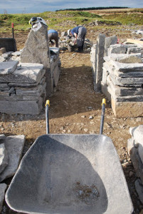 Showing the narrow straight entrance into the broch, with tall door uprights, seen from the vantage point of a dusty wheelbarrow.