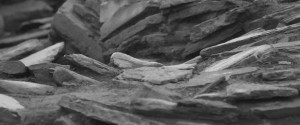 A black and white abstracted photo showing rock slabs sitting at different angles, forming graceful patterns on an archaeological dig site.