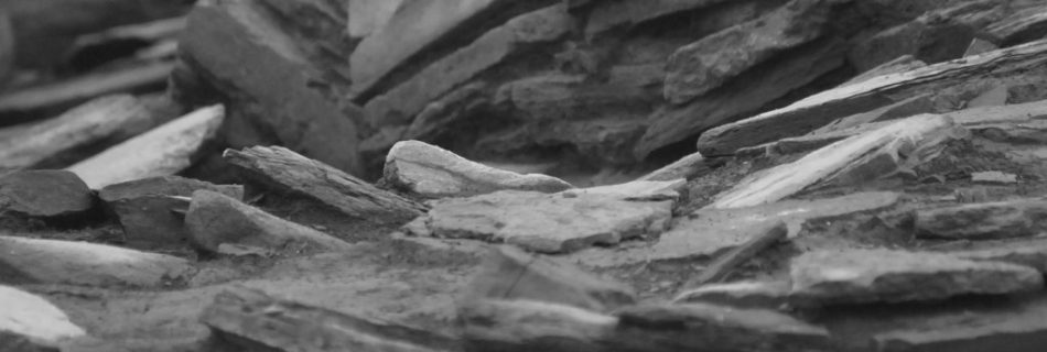 A black and white abstracted photo showing rock slabs sitting at different angles, forming graceful patterns on an archaeological dig site.