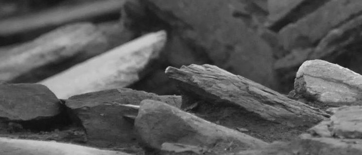 A black and white abstracted photo showing rock slabs sitting at different angles, forming graceful patterns on an archaeological dig site.