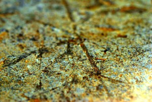A macro photo showing the man made carved straight lines, running at different angles, in the surface of sandstone found at an archaeological dig.