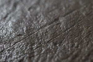 A close up black and white photo showing man made carved straight lines, running at different angles, in the surface of sandstone found at an archaeological dig.