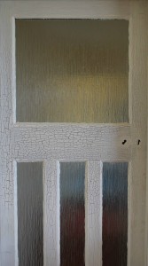A detail photo of an aged circa 1930s British interior wooden door with white and grey-green paint that is heavily grazed and cracked.